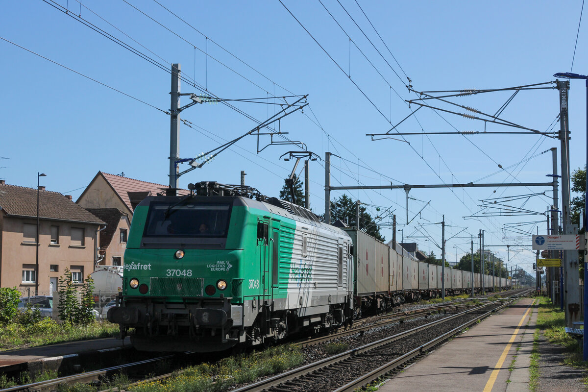 Hexafret 37048 verlässt nach einer Überholung durch einen Personenzug den Bahnhof Hochfelden (29.08.2025)