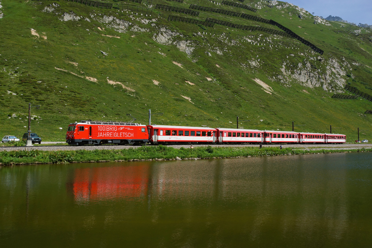 HGe 4/4 II 104 zieht am 19.07.2014 den Regio 831 dem Oberalpsee entlang Richtung Nätschen.