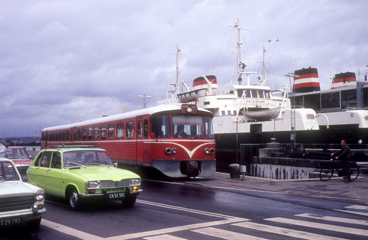 HHGB (Helsingør-Hornbæk-Gilleleje-Banen, auch Hornbækbanen genannt) im August 1976: Ein Triebzug bestehend aus einem Triebwagen Ym (hinten) und einem Steuerwagen Ys) fährt in der Havnegade (: Hafenstrasse) in Helsingør und nähert sich dem Zielbahnhof, dem Bahnhof Helsingør. Auf dem Bild befindet sich der Zug neben dem Fährbett der DSB-Fährschiffe, die die Fährlinie Helsingør - Helsingborg (in Schweden) bedienten. - Im Fährbett sieht man die Eisenbahnfähre  M/F Helsingør , die 1955 von der Helsingør Skibsværft gebaut wurde.
