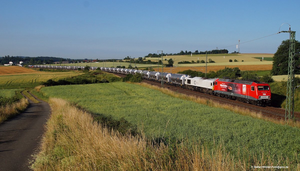 Hier kommt am 07.07.2015 das Objekt der Begierde um die Ecke. Der ZementExpress mit MEG 804 (BR156) und der Class77 rollt mit seinen neuen glänzenden Kesselwagen bei Feilitzsch auf dem falschen Gleis in den Morgen. Wer genau hinsieht, kann ganz hinten auf dem anderen Gleis den planmässigen EIB Vt 650 herannahen sehen.  Vielleicht 200 m hinter dem Fotografen hatte der Vt den Gz überholt. Es gibt noch ein Foto von dem Vt neben dem rollenden Gz....