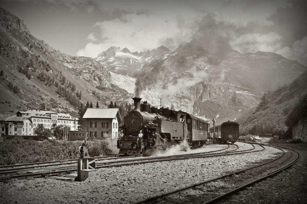 Hier nun eine Version in 1024 px mit etwas mehr Kontrast und Gletsch: 
Gletsch anno dazumal knnte man meinen, wrde nicht der kahle Fels im Hintergrund auf den strak zurckgegangen Rohne-Gletscher hinweisen. Die 1913 von der SLM gebaute HG 3/4 N 1  Furkahorn der DFB verlsst das 1759 mM gelegene Gletsch Richtung Oberwald. 5. August 13