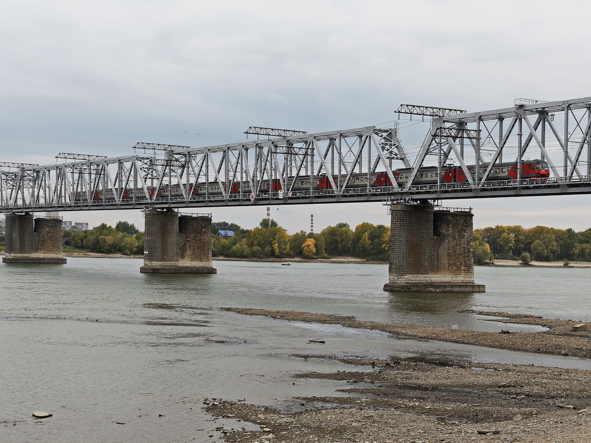 Hier überquert gerade ein Personenzug die Eisenbahnbrücke über den Ob in Nowosibirsk am 13. September 2017.