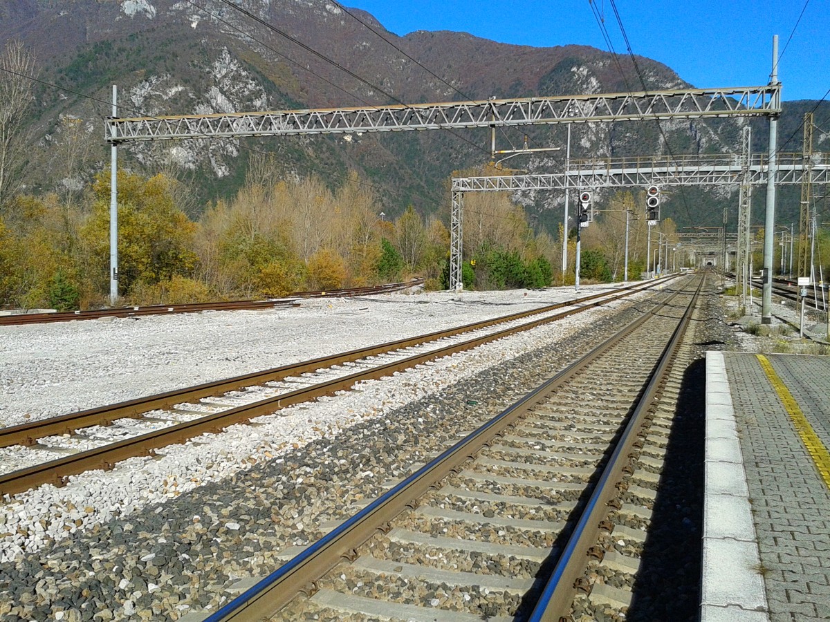 Hier zu sehen ist die neue Pontebbana im Bahnhof von Carnia, mit Blick in Richtung des Galleria (Tunnel) Camoiolo-M. Palis. Nach diesem Bahnhof teilen sich die alte und neu Pontebbana auf. Das Gleis ganz links, dieses in den Büschen verschwindet gehört zur 1968 stillgelegten Strecke von Carnia nach Villa Santina. Diese Strecke wurde 1976 bis zu einer Fabrik in Tolmezzo wieder in Betrieb genommen, diente aber nur mehr als Anschlussbahn und wurde am 9. Mai 2010 wieder stillgelegt.
Einst hatte die Strecke in Tolmezzo Anschluss an die 1931 stillgelegte 750 mm-Strecke nach Moscardo.
In Villa Santina dem ehemaligen Endbahnhof der Strecke bestand Anschluss an die 1920 stillgelegte 750 mm-Strecke nach Comeglians und an die ehemalige 600 mm-Strecke nach Ampezzo.