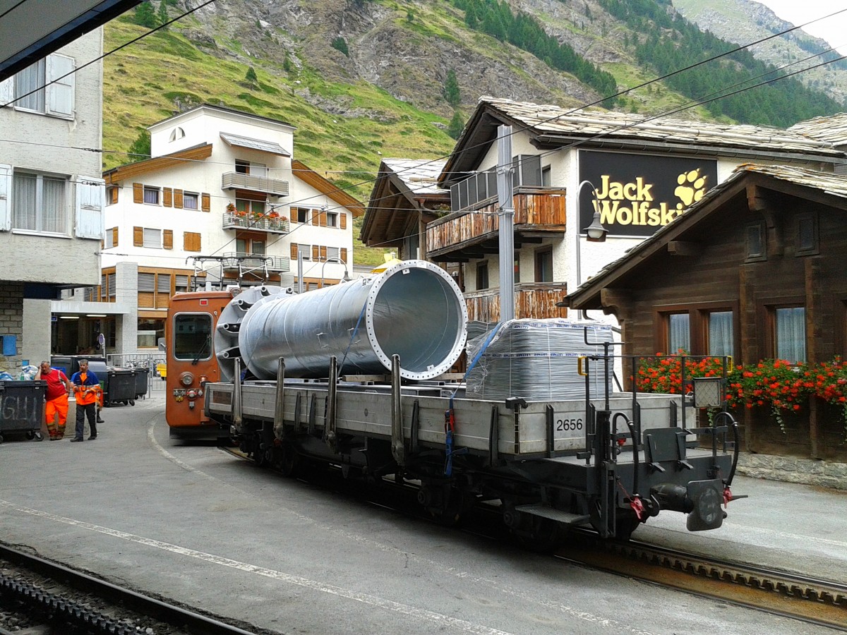 Hier zu sehnen ist ein Bhe 4/4 mit einem Wagon, beladen mit einem Teil einer Liftstütze. Aufgenommen am 22.7.2015 im Bahnhof Zermatt (GGB).