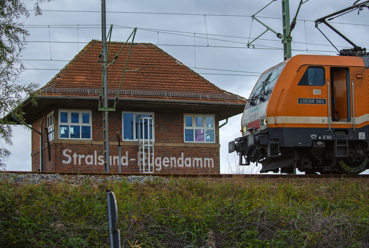 Hinter dem Bahndamm ragt das Stellwerk Stralsund Rügendamm hervor, an dem die Locon Lok 501 auf das Ende der Rangierarbeiten wartet. - 19.09.2016
