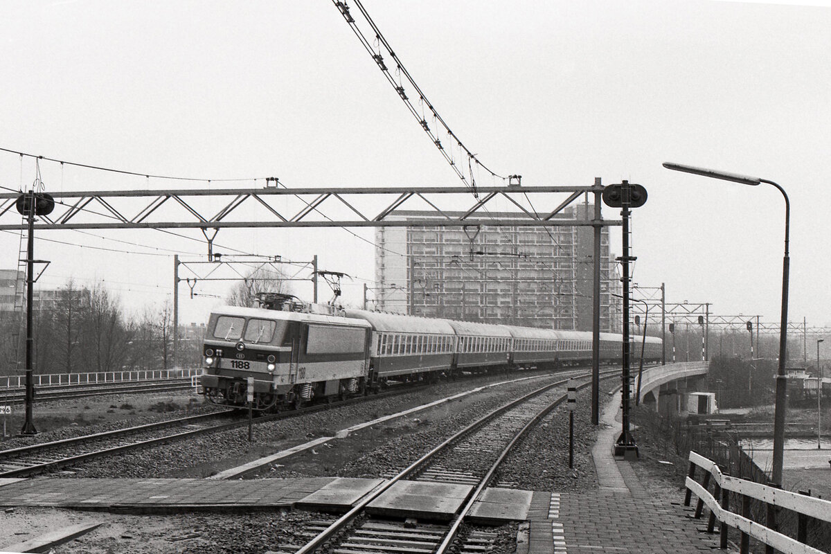 Historische Aufnahme der Belgischen Reihe 11, als die Loks sich noch in Ablieferungsphase befanden. Beim Testen unter 1500V des Niederländischen Netzes wurde als Last eine DB Wagengruppe verwendet. Hier der Zug bei Durchfahrt in Schiedam-Rotterdam West am 20.03.1986, 13.45u. Lok NMBS 1188 mit Testzug von Amsterdam Dijksgracht nach Roosendaal. Scan (Bild 94196, Ilford FP4).