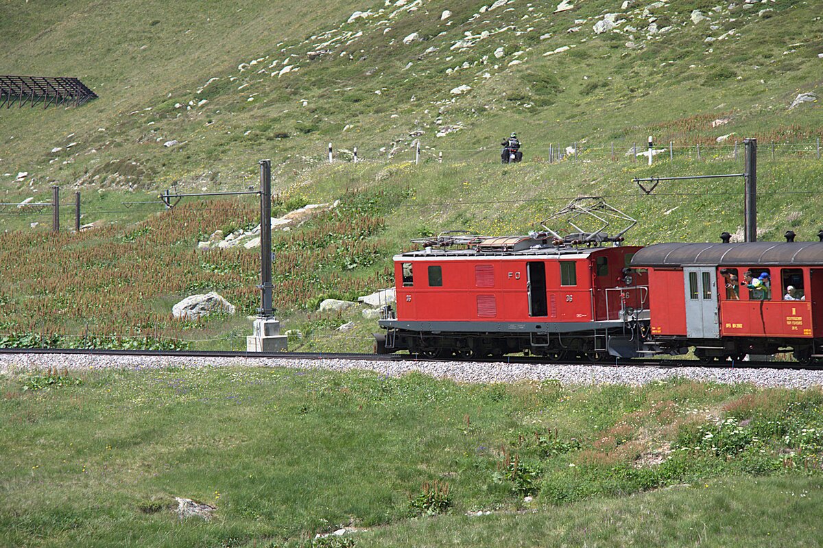 Historische Lokomotive in einer Berglandschaft an einem Alpenpass. Der Sonderzug zum Jubil�um 100 Jahre FO hat am 05.07.2026 die Gallerie am Oberalppass verlassen und f�hrt jetzt Richtung Andermatt.
Die Strasse liegt oberhalb der Bahnstrecke und ist bei Motorradfahrern sehr beliebt.