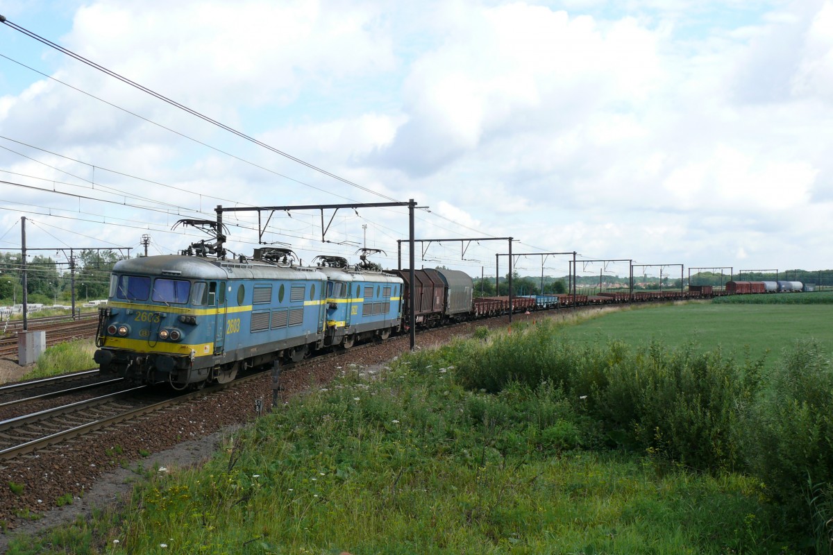 HLE 2603 und 2622 ziehen einen langen Güterzug vom Antwerpener Hafen kommend, und biegen hier nach Antwerpen-Noorderdokken ab. Das Bild entstand am 17/07/2010.