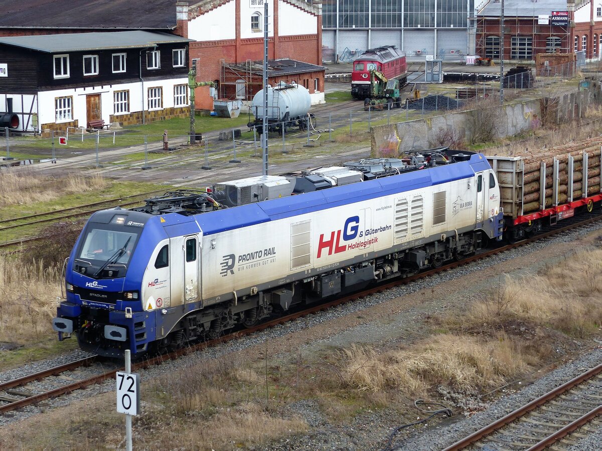 Holzlogistik und Güterbahn HLG, Stadler Eurodual 159 216-1 ( 9080 2159 216-1 D-RCM ) verlässt Gera am 8.2.2022 mit einem Langholzzug. Am Ende des Zuges rollt einer 185er E-Lok mit, welche ab Jena unterstützend mitwirkt.