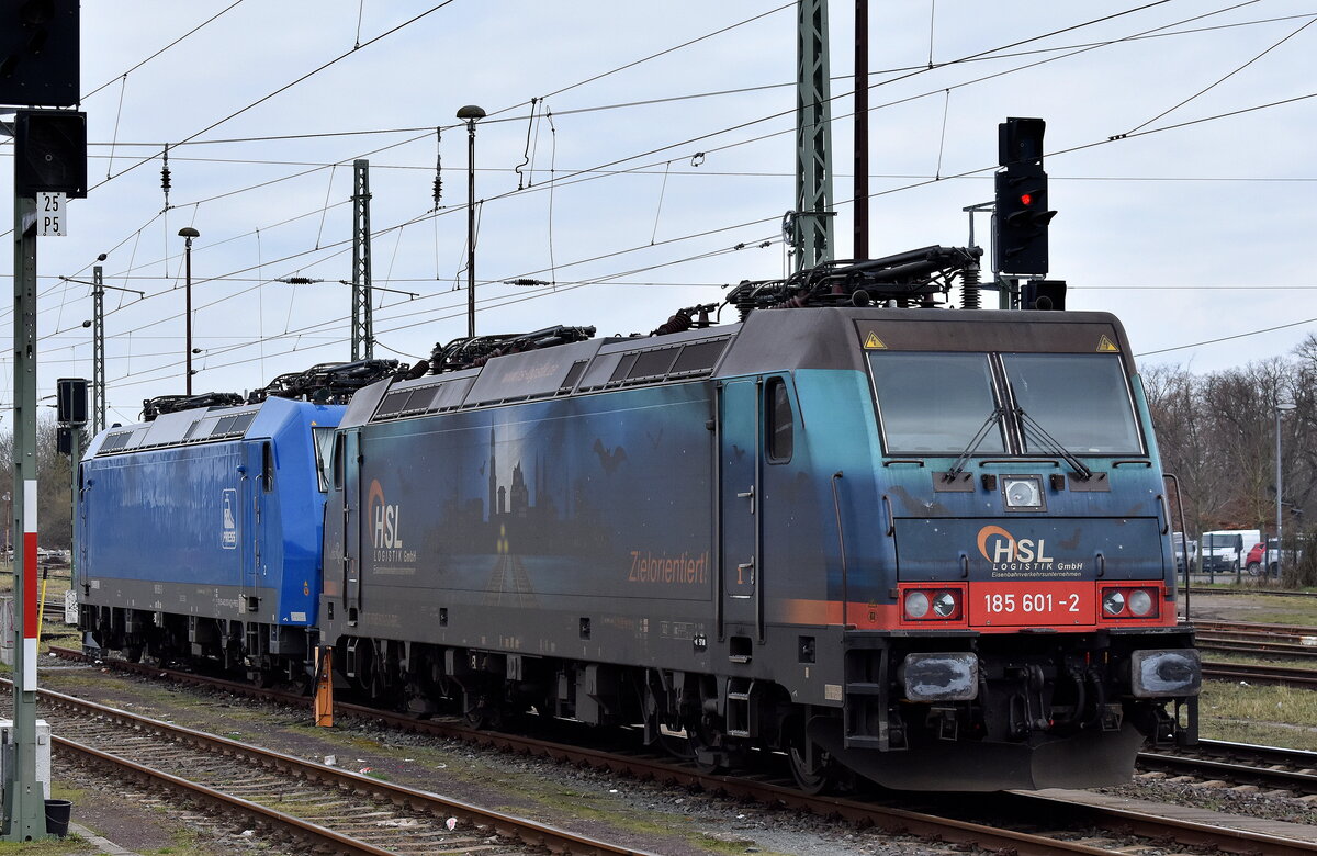 HSL Logistik GmbH, Hamburg [D] mit der  185 601-2  [NVR-Nummer: 91 80 6185 601-2 D-BRLL] + PRESS - Eisenbahn-Bau- and Betriebsgesellschaft Pressnitztalbahn mbH, Jöhstadt [D] mit ihrer  185 063-3  [NVR-Nummer: 91 85 4482 033-8 CH-PRESS] abgestellt am 21.02.24 neben dem Bahnhof Stendal Hbf.