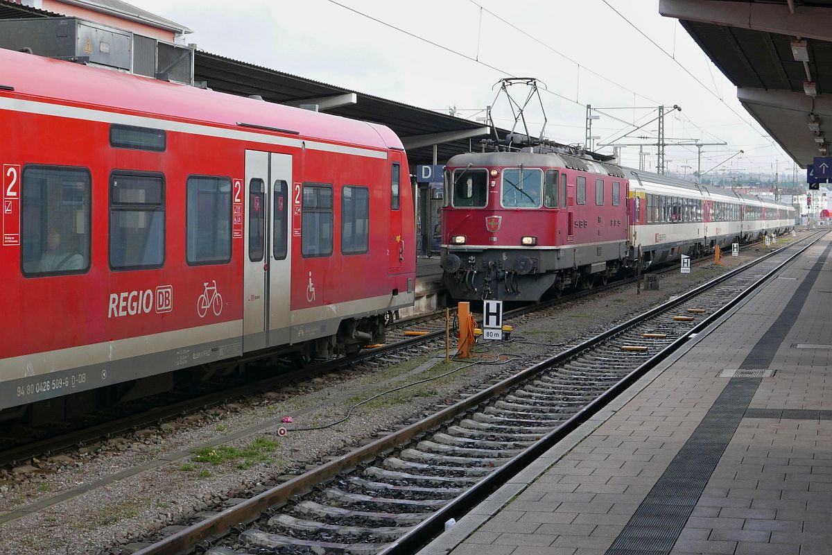 IC 483 und IC 280 in Singen (Hohentwiel) (|) - Aus der Abstellung kommend hat Re 4/4 II 11111 die Wagen des IC 483 nach Zürich HB hinter die nach Schaffhausen fahrende Regionalbahn gezogen, damit unmittelbar nach Abfahrt der RB die Wagen zum Einstieg der Passagiere in den IC an den vorgegebenen Bahnsteigbereich gezogen werden können (30.12.2020).