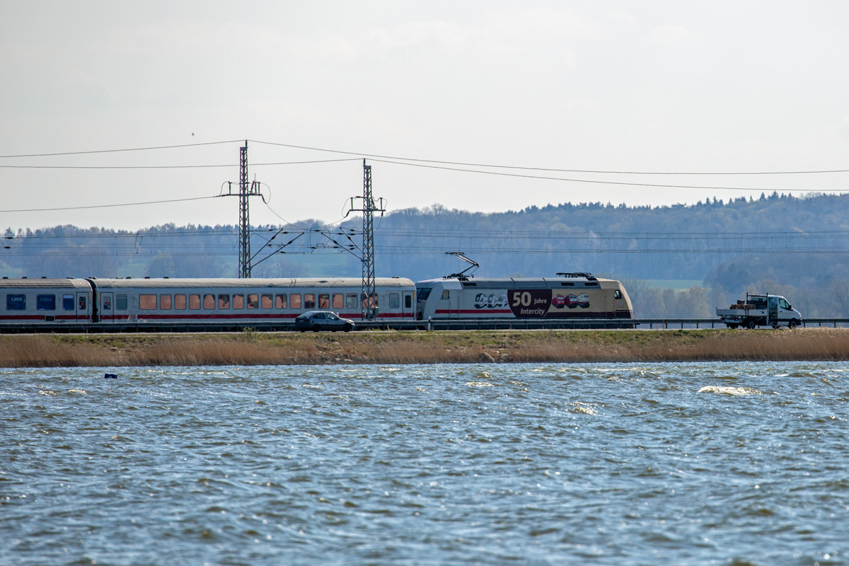 IC mit der Werbelok „50 Jahre Intercity“ fährt in Lietzow parallel zur B 96 zwischen dem Kleinen-und Großen Jasmunder Bodden. Aufnahme leider bei etwas Gegenlicht. - 26.04.2022