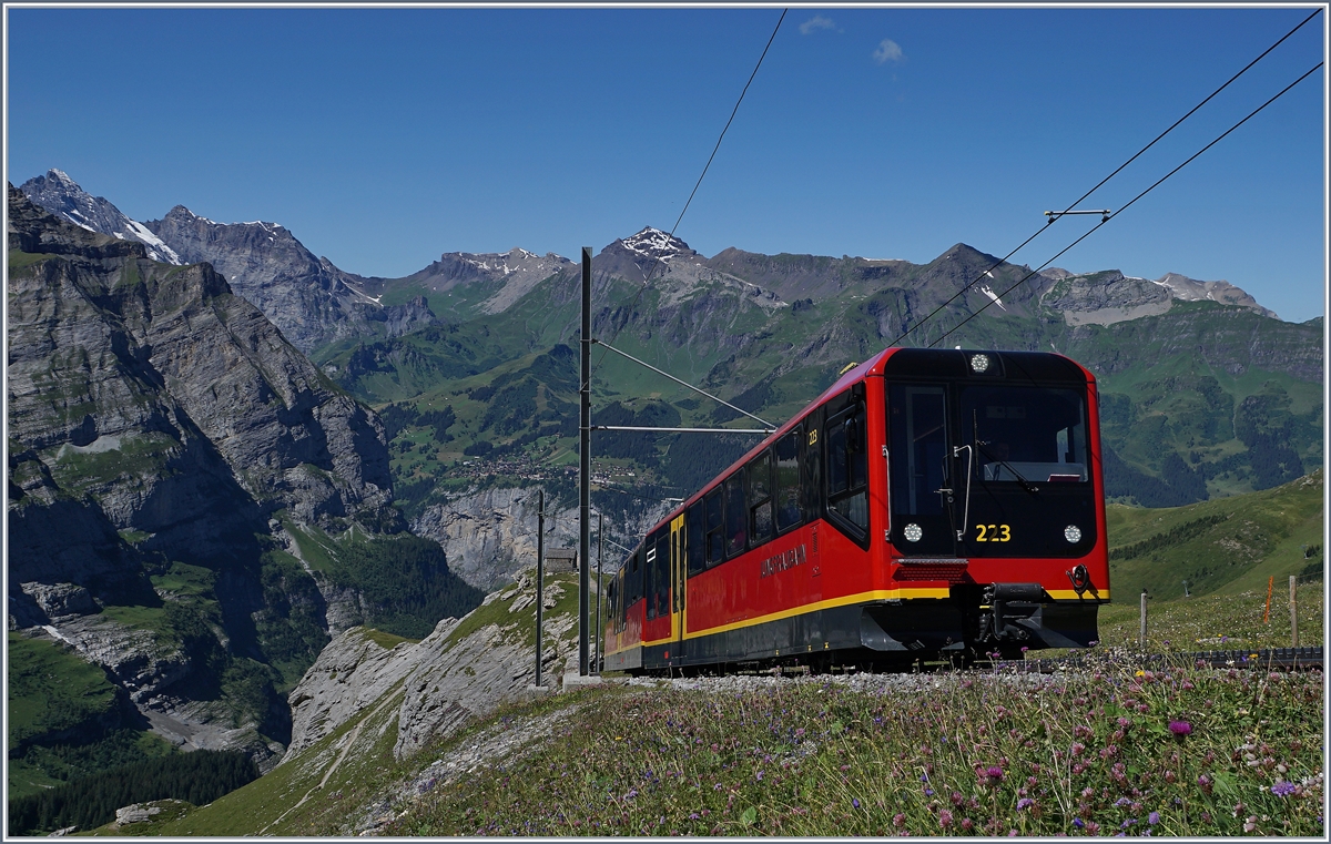 Ich finde der neuen Jungfraubahn Triebzug Bhe 4/8 passt perfekt in die Jungfrauregion. Und weisst mit seinen Berner Farben unmissverständlich darauf hin, dass man sich im Berner Oberland befindet, auch wenn die Station Jungfraujoch im Wallis liegt.
Hier erreicht der Beh 4/8 223 in Kürze die Station Eigergletscher. Im Hintergrund ist Mürren zu erkennen, was insofern von Bedeutung ist, als dass dem Bauherrn der Jungfraubahn dort die Idee zur Linienführung der Bahn auf die Jungfrau kam. Trotz des grossen Erfolges der Bahn, hat man es bisher versäumt, sie bis zur geplanten Gipfelstation fertig zu bauen.
8. August 2016