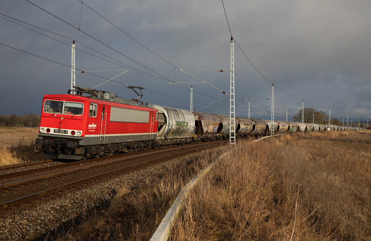 IGE/BLC24 mit LDK 155 059 und Leergetreidezug von Mukran am 17.01.2023 bei Samtens. Ein schwacher Regenbogen ließ sich auch im Hintergrund erblicken.
