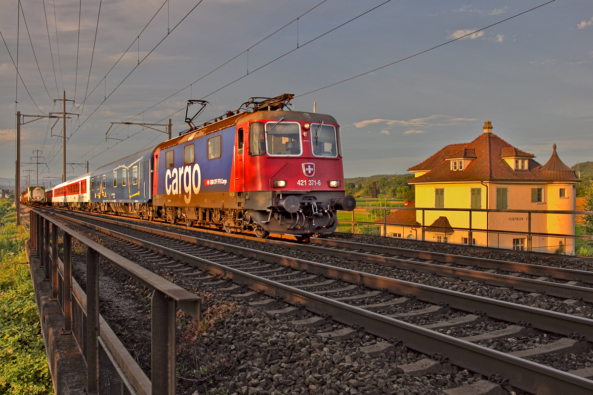 Im allerletzten Büchsenlicht fährt die Re 421 371-6 mit dem EN von Zürich HB nach Prag in Keuzung eines Güterzuges beim Pumpwerk Löli in Kaiseraugst vorüber.Bild vom 26.6.2015