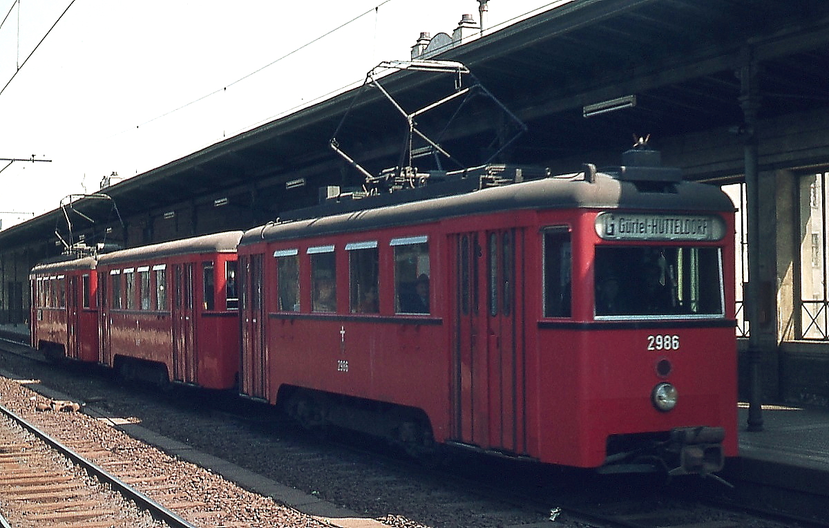 Im April 1974 ist ein Stadtbahnzug mit dem N1 2986 an der Spitze als Linie G vom Gürtel nach Hütteldorf unterwegs. Die Wiener Stadtbahn wurde 1898 als dampfbetriebene Vollbahn eröffnet, 1924 wurden die Wiental-, Donaukanal- und Gürtellinie an die Gemeinde Wien verpachtet, die die Strecken elektrifizierte. Ab 1976 wurden die Linien auf U-Bahn-Betrieb umgebaut, als letzte wurde die Linie G zwischen Gumpendorfer Straße und Heiligenstadt im Oktober 1989 eingestellt (heute U6). Die ursprünglichen Stadtbahnwagen Typ N erhielten nach dem Krieg Stahlaufbauten und wurden danach als N1 bezeichnet. Wie man sieht, herrschte auf der Stadtbahn Linksverkehr.