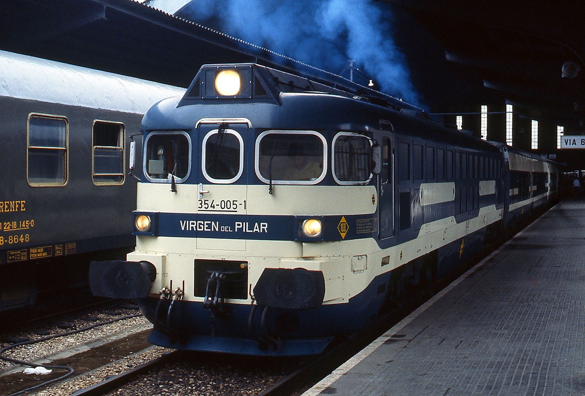 Im April 1984 steht die 354-005-1  Virgen del Pilar  mit einer Talgo IV (Talgo Pendular)-Garnitur abfahrbereit im Bahnhof von La Coruna. Krauss-Maffei lieferte 1983/1984 insgesamt 8 dieser Lokomotiven an die spanische Staatsbahn.