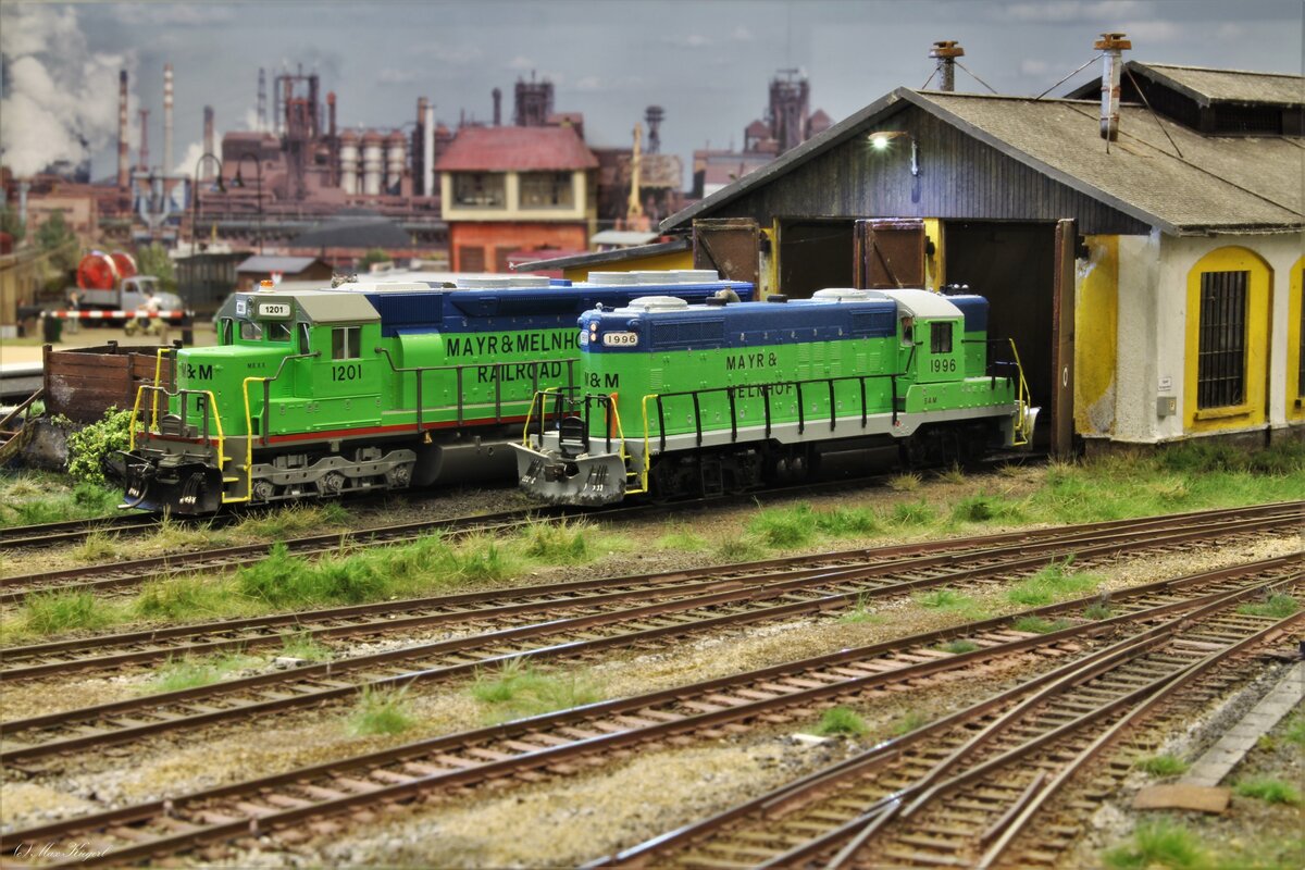 Im August 2023 stehen beim Lokschuppen in Elliswood Yard die GP9 #1996  Sam  und die SD45 #1201  Mexx  der Mayr&Melnhof Railroad.
Die Geep #1996 wird dich in Kürze auf die Reise machen und verschiedene Anschlussbahnen entlang der Elliswood&Shoetown Branchline bedienen.