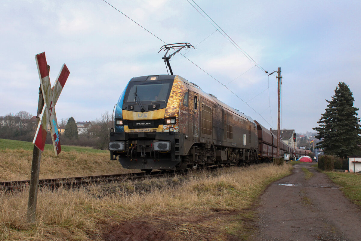 Im Bahnhof Merchweiler zweigt von der Fischbachtalbahn die am 1. Oktober 1891 eröffnete Stichstrecke zur Grube Göttelborn ab. Die Strecke wurde 1965 elektrifiziert und wird seit der Stilllegung der Grube Göttelborn nur noch selten genutzt, wenn das Kraftwerk Weiher bedient werden muss. Der 09.02.2026 war einer dieser Tage und 2019 316 war damit beauftragt, drei Kohlezüge nach Göttelborn zu bringen. Mit dem ersten der drei Züge ist sie hier kurz nach dem Verlassen der Hauptstrecke bei Merchweiler zu sehen.