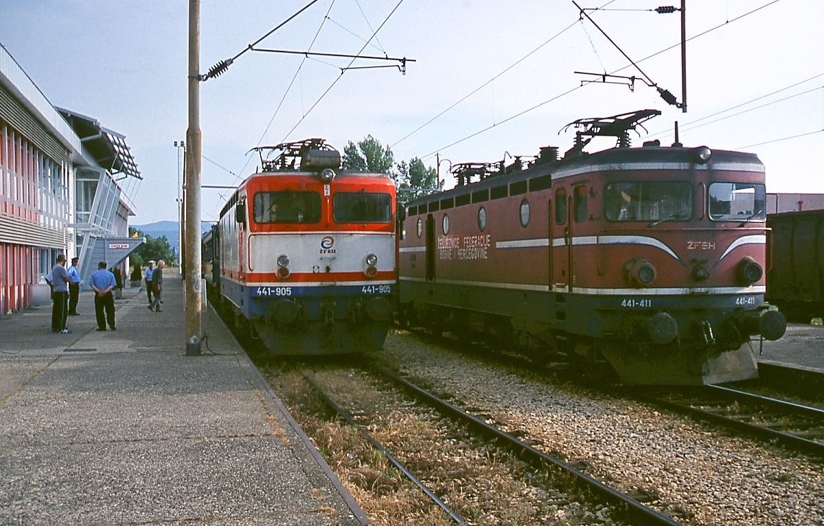 Im bosnisch-herzegowinischen Grenzbahnhof Caplijna übernimmt die 441-905 der ZFBH (Željeznice Federacije Bosne i Hercegovine) am 18.05.2009 den mit der 441 1 384 aus Ploce angekommenen Schnellzug zur Weiterbeförderung nach Sarajevo. Die 441-9 wurden bei Rade Koncar in Zagreb auf Thyristorsteuerung umgebaut und erhielten einen weissen Anstrich mit blauem Untergestell und roten Zierlinien. Die daneben stehende 441-411 gehört zur Variante 441-4, die der Variante 441-3 entsprach, zusätzlich aber noch mit einer Spurkranzschmierung ausgerüstet wurde. 24 Stück wurden zwischen 1967 und 1969 und weitere 10 1987 gebaut.
