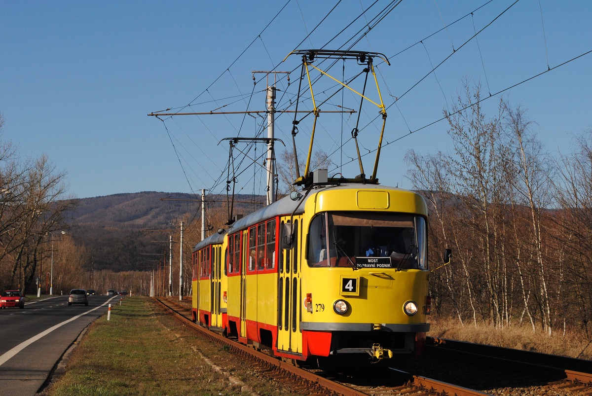 Im ehemaligen bzw. rekultivierten Tagbaugebiet von Zaluzi erreicht das vom T3SUCS 279 geführte Tandem der Linie 4 die Haltestelle areal Hlubina, den Hintergrund bildet das Erzgebirge. (20.03.2019)