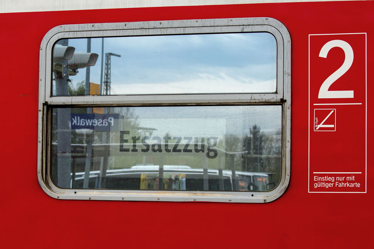 Im Fenster des abgestellten Zuges auf dem Bahnhof Pasewalk hängt das Schild mit dem Hinweis „Ersatzzug“. In der Spiegelung sieht man den Ort und der Grund wird über die Lautsprecher angekündigt. - 05.05.2015
