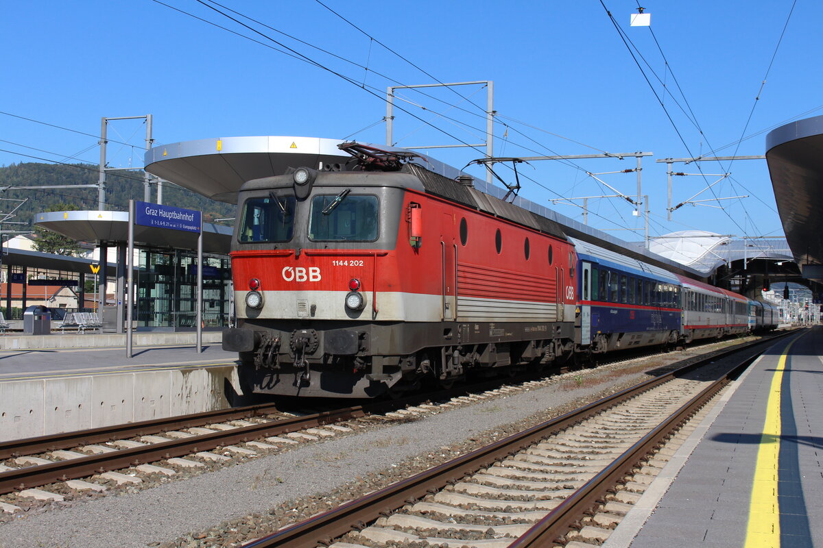 Im Frühherbstlichen Mittagslicht des 19.9.2021 steht die 1144 202 mit dem EC151  Emona  von Wien Hbf nach Ljubljana und mit Kurswagen nach Trieste Centrale in Graz Hbf und wartet auf die Weiterfahrt nach Spielfeld-Straß.
Die Abfahrt verzögerte sich wegen einem verspäteten Anschluss um einige Minuten.