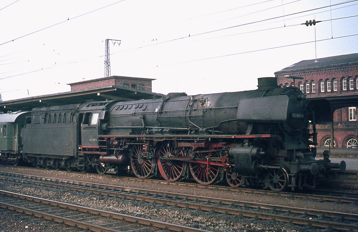 Im Frühjahr 1975 ist die 012 063-4 mit einem Eilzug aus Emden im Bahnhof Rheine angekommen. In den letzten Betriebsmonaten waren diese stolzen Maschinen leider nicht mehr im besten Pflegezustand unterwegs.