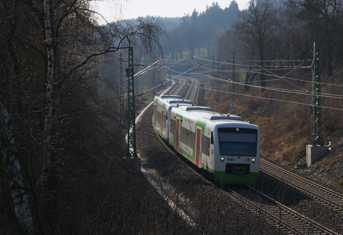 Im Gegenlicht rollen die beiden RegioShuttle der Erfurter Bahn das Gefälle zwischen Schönberg/Vogtland und Mehltheuer hinab. Gleich unterqueren die beiden, vorne VT 301, der Elster-Saale bahn Hof - Gera die Elmbrücke bei Drochaus. 14.03.2014 - Bahnstrecke 6362 Leipzig - Hof.