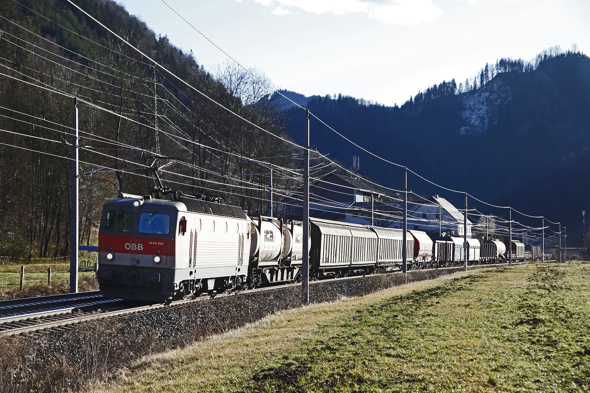 Im Gegenlicht zieht 1144 081 einen gemischten Güterzug zwischen Perngg und Bruck an der Mur Richtung Norden. Das Bild entstand am 30.01.2018.