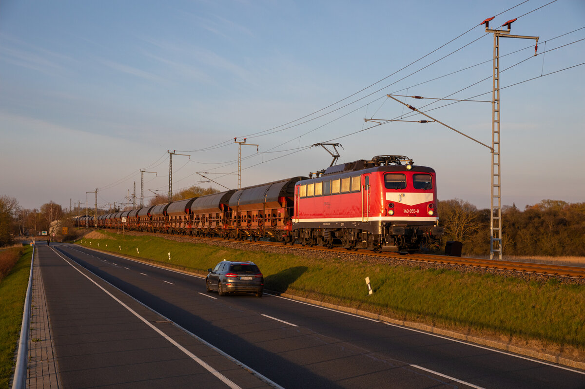 Im goldenen Abendlicht, des 18.04.2023 rollte die 140 855 der Triangula Logistik mit einem leeren Getreidezug aus Mukran, bei Altefähr über den Rügendamm.
