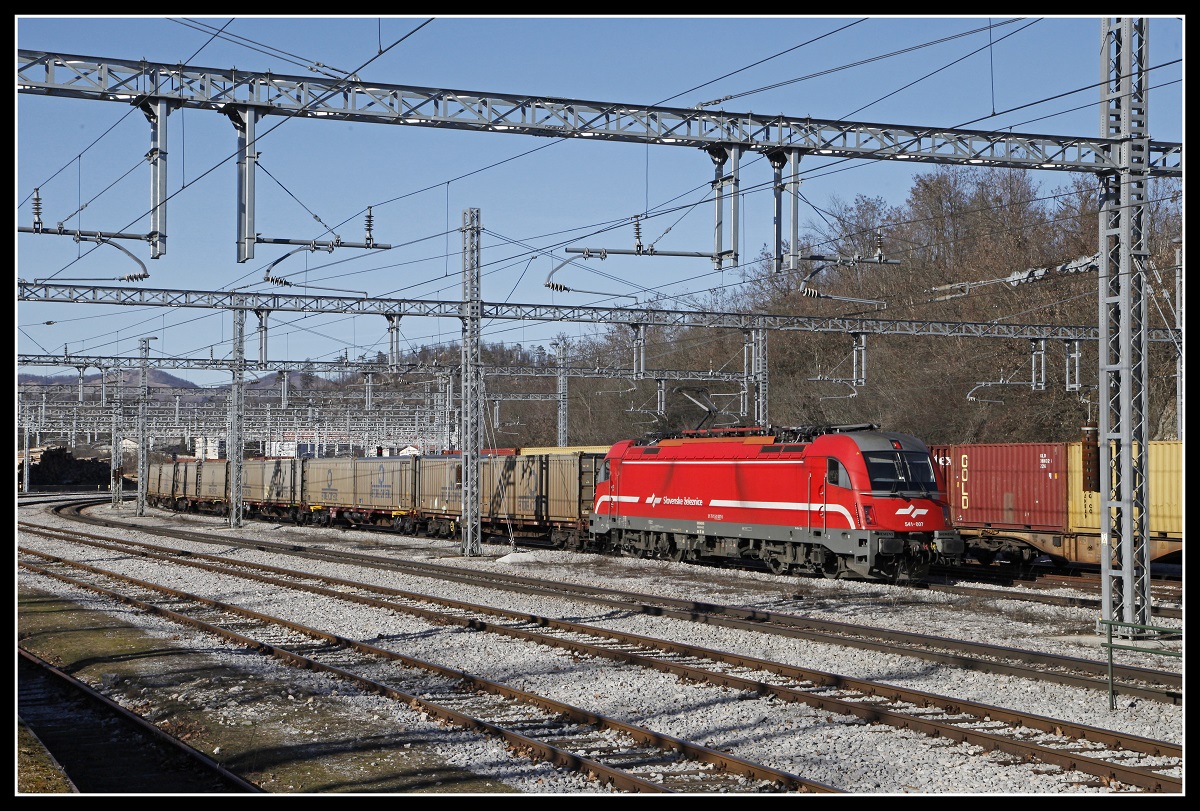 Im Jahr 2014 wurde die Oberleitung des Bahnhofes Postojna durch einen Eisregen zerstört.Der wuchtige Neubau der Fahrleitung beherscht seitdem die Szenerie in diesem Bahnhof. Hier zu sehen mit der 541-007 mit Güterzug am 13.02.2019.