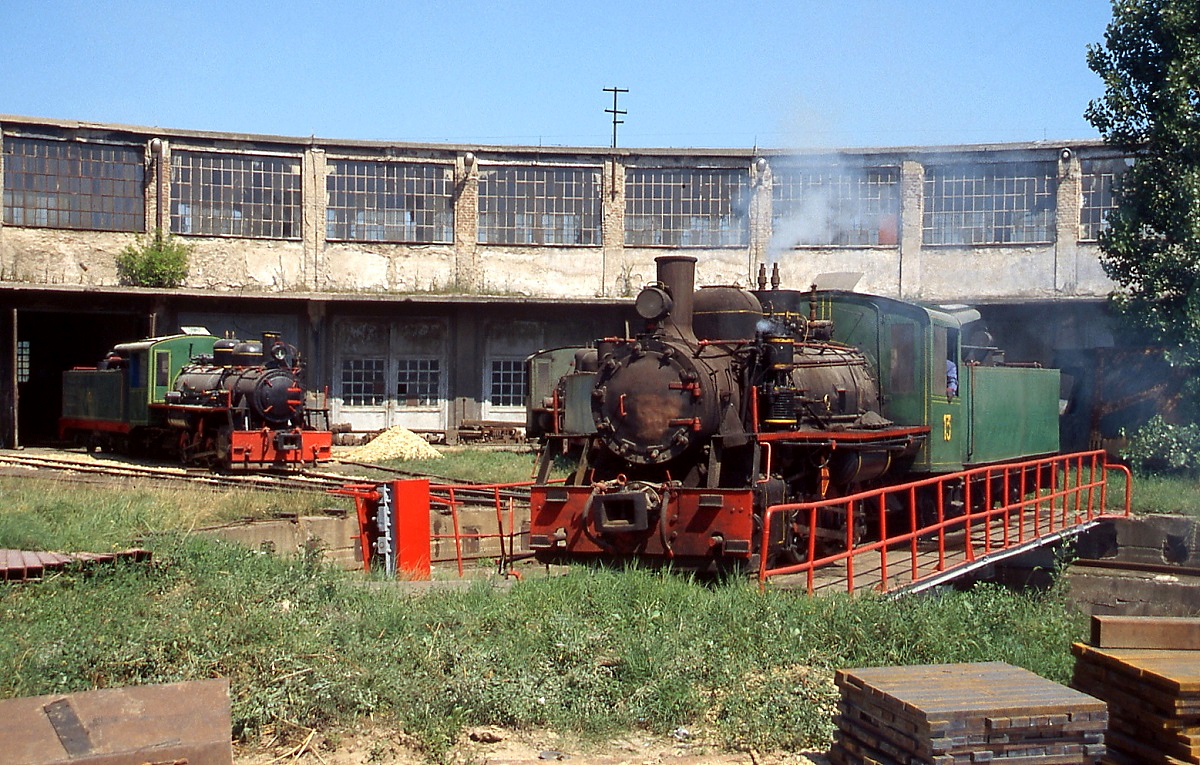 Im Juli 2005 wendet Lok 13 auf der Drehscheibe des Kohletagebaues Kostolac. Diese Lokomotiven wurden 1946 von der UNRRA (United Nations Relief and Rehabilitation Administration) geliefert. Vor dem für eine 900 mm-Bahn beachtlichen Lokschuppen steht eine weitere Lokomotive.