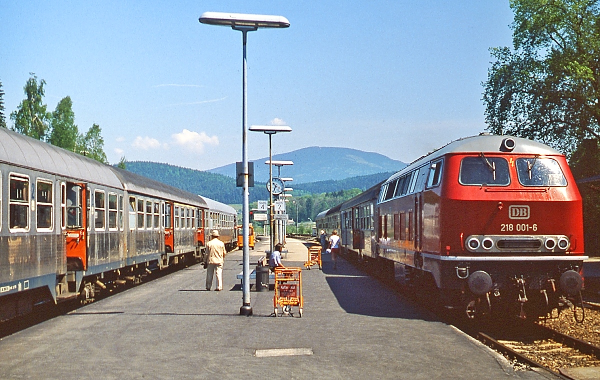 Im Mai 1980 kreuzen sich im Bahnhof Zwiesel die Züge von Plattling nach Bayerisch Eisenstein bzw. in der Gegenrichtung. Vor dem Zug nach Plattling steht die 218 001-6. Die Lok war die erste von 12 Prototypen, denen 319 Serienlokomotiven folgten. Sie wurde am 17.05.1968 beim Bw Regensburg in Dienst gestellt, wo sie bis zu ihrer Ausmusterung am 31.01.2000 verblieb.