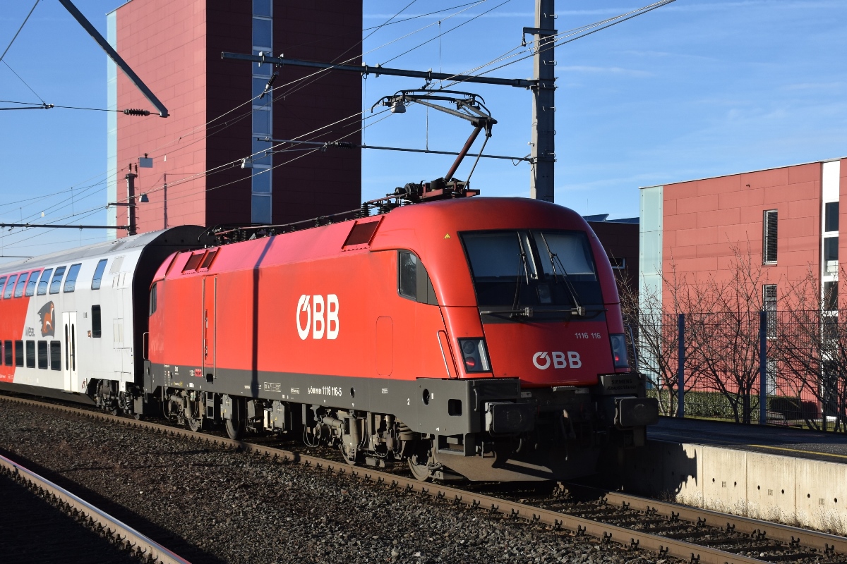 Im Nahverkehr in Vorarlberg gibt es 2 Möglichkeiten: S-Bahn (mit Halt in allen Stationen) oder Regional-Express (REX, lässt kleinere Stationen aus). In beiden Fällen kommen zwar in erster Linie Talent-Triebzüge der BR 4024 zum Einsatz, aber man kann auch andere Fahrzeuge antreffen.
1116.116 schiebt am 05.01.2018 ihren REX 5565 (von Bregenz nach Bludenz) ohne Halt durch die Haltestelle Dornbirn-Schoren in Richtung Feldkirch.
