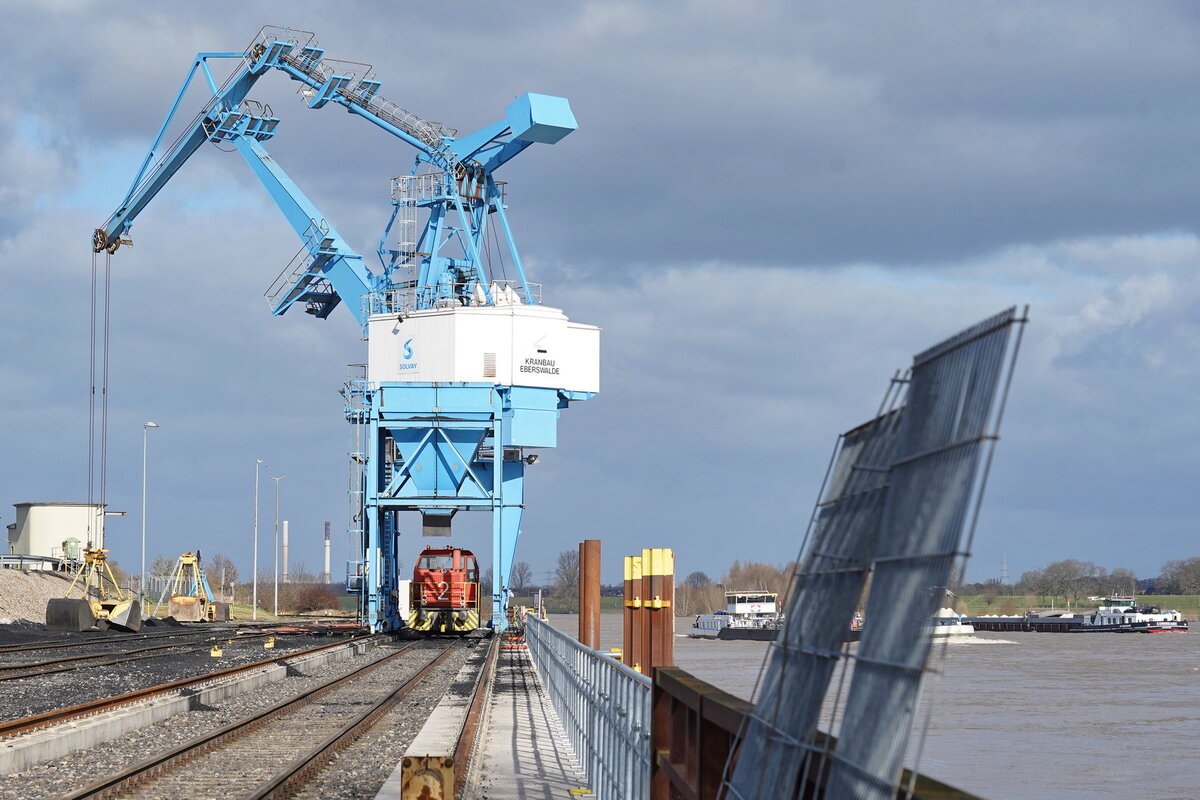 Im Rheinhafen Rheinberg-Ossenberg ist die Solvay-Werklok 2 (ehemals Thyssen-Edelstahlwerke Lok-1) vom Typ G761C (MaK1980FNr.700036) unter dem eindrücklichen Kran zu sehen.
Die Werkbahn verbindet einerseits das Werk mit dem von den Solvay-Werken betriebenen Rheinhafen und andererseits mit dem DB-Übergabebahnhof Millingen an der Niederrheinstrecke Rheinhausen–Kleve.

2022-02-11 Rheinberg-Ossenberg Rheinhafen (außerhalb an der Hafenumgrenzung am Rhein)

