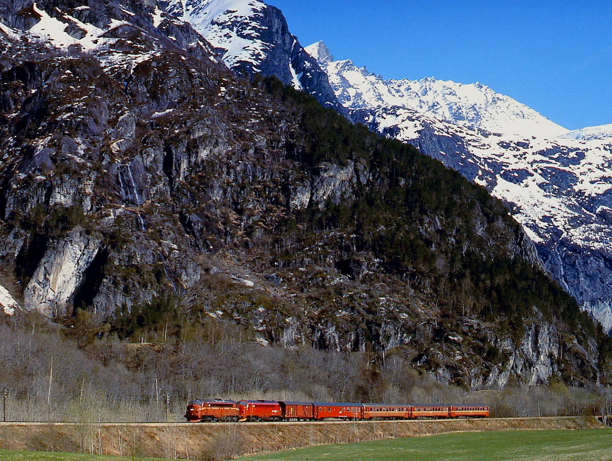 Im Romsdalen kurz vor Andalsnes isr eine Di 3a-Doppeltraktion mit einem Personenzug im Mai 1988 unterwegs. Der Gebirgszug im Hintergrund erreicht zwar  nur  die Höhe von knapp 1.800 m Höhe, trotzdem scheint bei diesem Anblick die Bezeichnung  Romsdaler Alpen  gerechtfertigt.
