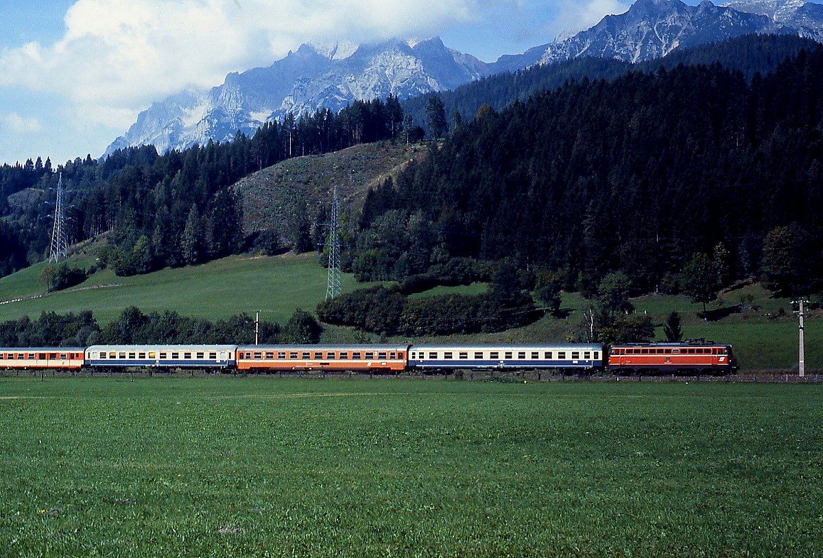 Im September 1986 ist eine 1042 mit einer bunten Garnitur von DB- und ÖBB-Wagen im Ennstal zwischen Schladming und Haus unterwegs