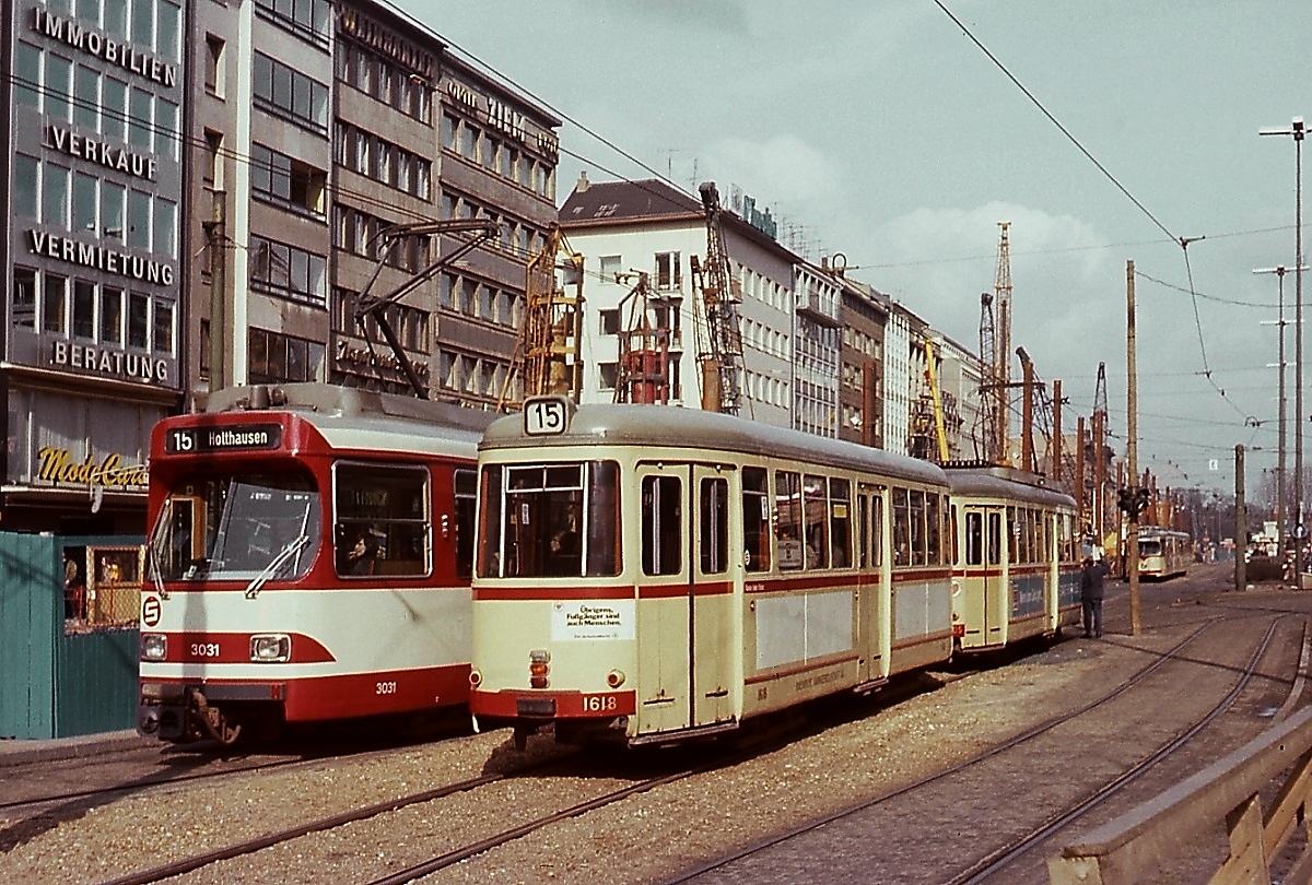 Im Sommer 1979 begegnen sich im Sommer 1979 zwei Rheinbahn-Züge der Linie 15 auf der Heinrich-Heine-Allee, links der fast noch nagelneue GT8S 3031, daneben ein Vierachserzug mit dem Bw 1618 am Schluss. Die Rammen im Hintergrund sind ein sichtbares Zeichen, dass die Arbeiten für den U-Bahn-Bau begonnen haben. Kurz danach wurde das vom GT8S befahrene Gleis stillgelegt und durch eine neue Streckenführung durch die Bolker- und Hunsrückenstraße ersetzt.