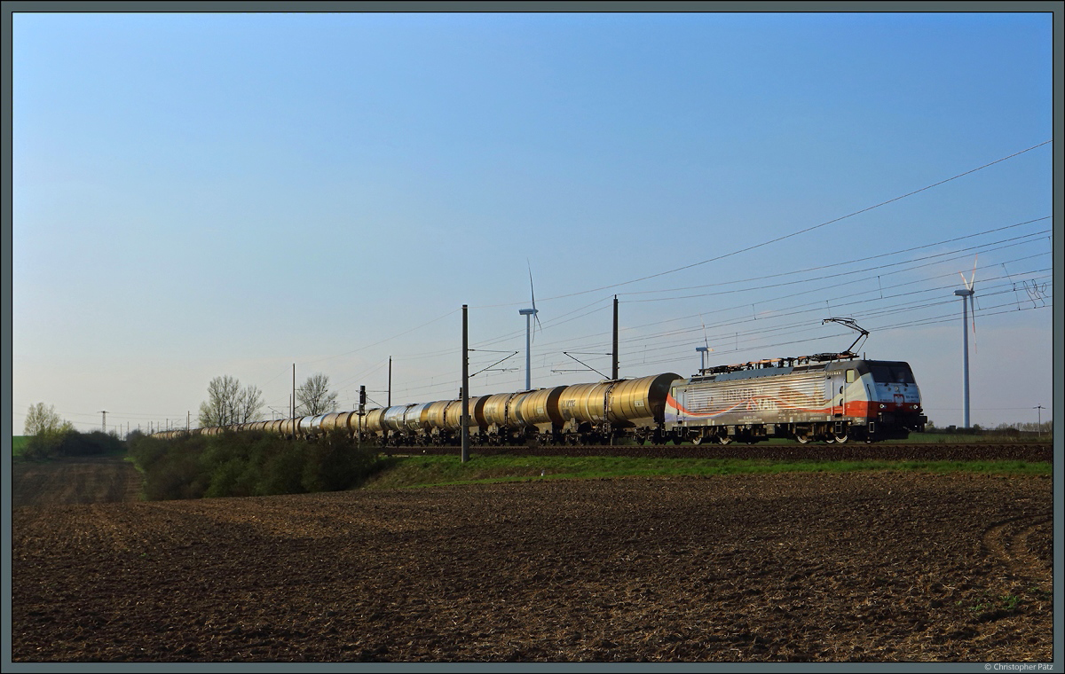 Im Streiflicht zieht 189 213 der LTE Netherlands ihren Kesselzug an den für Sachsen-Anhalt typischen Windrädern vorbei. (bei Wellen, 07.04.2019)
