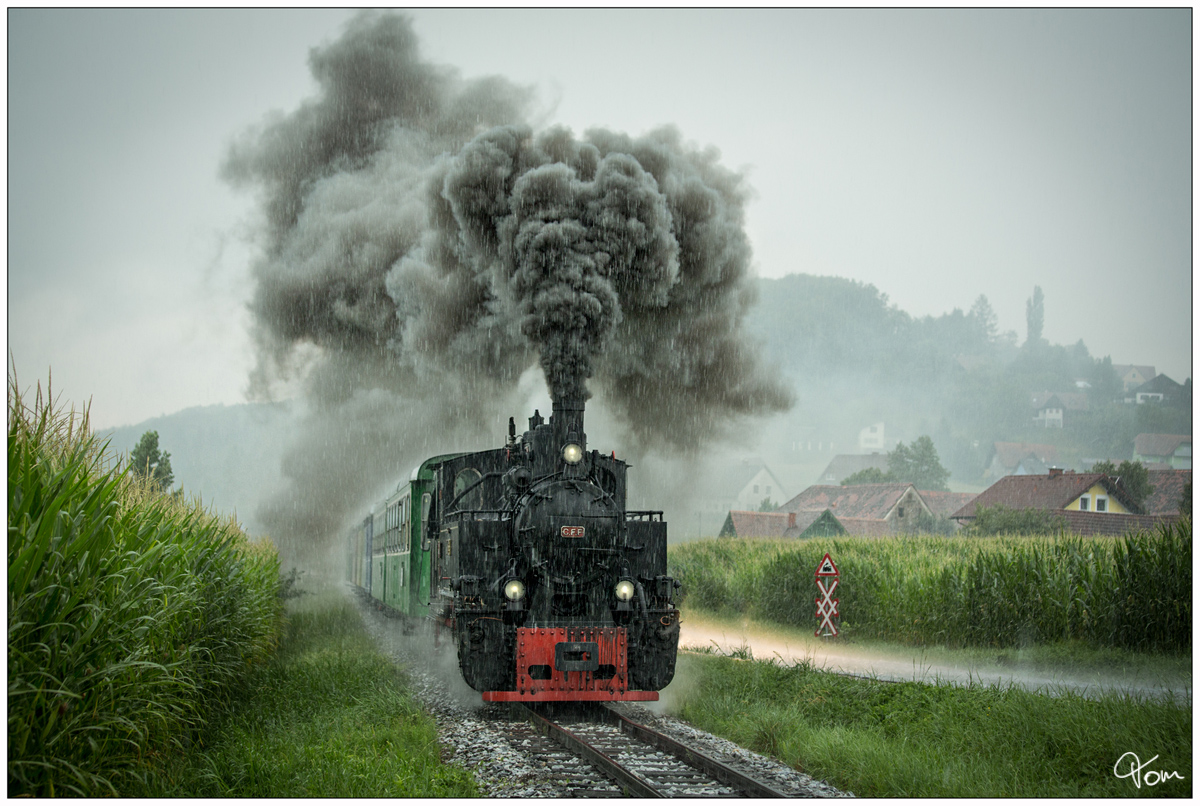 Im strömenden Regen, fährt die CFF Dampflok 764 411R Reghin mit dem Stainzer Flascherlzug von Preding nach Stainz, hier zu sehen bei einer imposanten Ausfahrt aus der Haltestelle Kraubath. 
27.07.2019