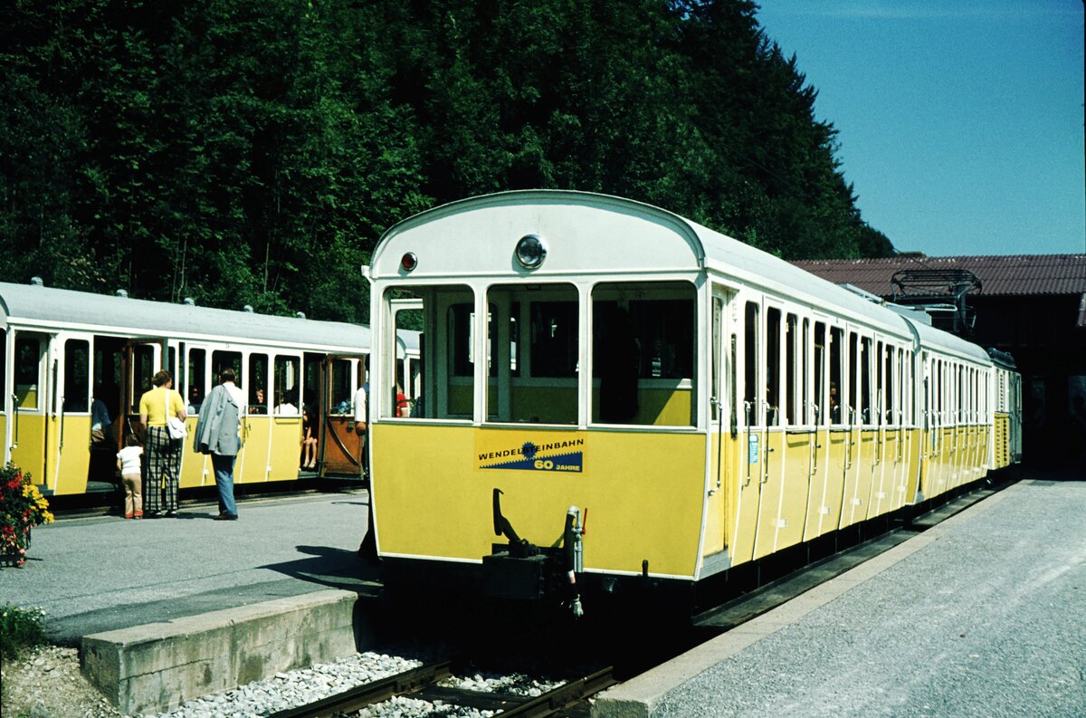 Im Talbhf. Waching__16-08-1973__Wie bei der Münster-Schlucht-Bahn wurde auch das für die Wendelsteinbahn errichtete Kraftwerk (hier mit Wasserkraft) gleich für die Stromversorgung der umliegenden Gemeinden vorgesehen. 1961 wurde der Abschnitt vom Bahnhof Brannenburg (Gleis an Gleis mit der Hauptbahn) bis zum heutigen Talbahnhof im Ortsteil Waching aufgegeben.
