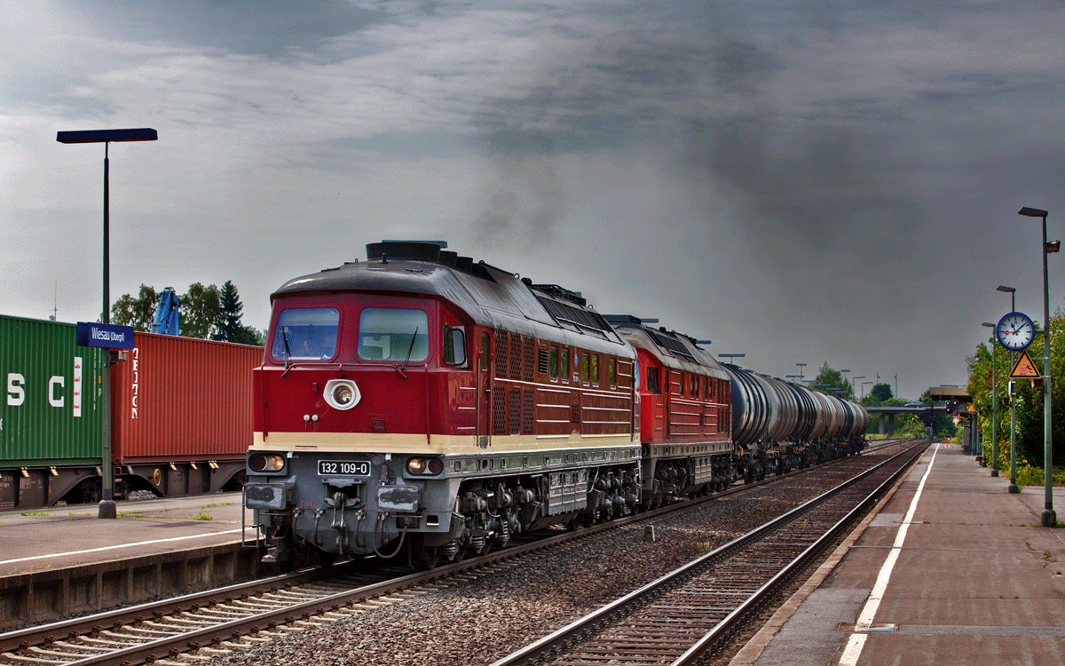 Im vollen Gegenlicht donnert eine Doppeltraktion bestehend aus den Diesellokomotiven LEG 132 109-0 / 232 239-4 mit einem Kesselwagenzug und einer herrlichen Abgaswolke durch den Bahnhof von Wiesau.Bild vom 2.6.2017