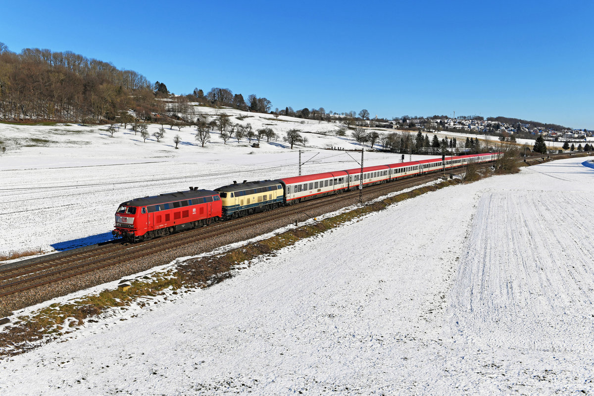 Im Winter 2021 verkehrte der IC 118/119 für einige Wochen wieder über Lindau hinaus bis nach Dortmund. Da der Bestand an einsatzfähigen 218ern in Ulm und Kempten für den gestiegenen Fahrzeugbedarf nicht ausreichte, wurde in bewährter Manier auf Maschinen der Railsystems RP GmbH aus Gotha zurückgegriffen. Erfreulich war, daß diesmal auch eine orientrot lackierte Vertreterin der Baureihe in Gestalt der 218 319 zum Einsatz kam. Am 13. Februar 2021 konnte ich bei Nassachmühle im leicht angezuckerten Filstal die besagte Maschine führend vor der ozeanblau-beigen 218 489 mit dem IC 118 auf der Fahrt nach Stuttgart HBF aufnehmen. Interessantes Detail bei der 218 319 ist die Lüfteranlage der Bauart Voith, deren aufgestellte Lamellen auf dem Dach gut erkennbar sind.