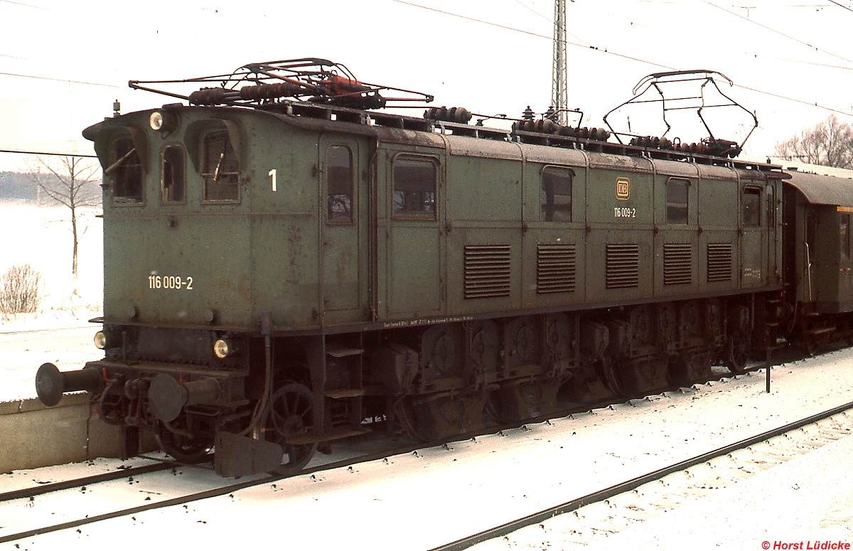 Im Winterfahrplan 1977/78 wurden die letzten 116 an Samstagen noch in einem eintägigen Umlauf eingesetzt, der Nahverkehrsleistungen zwischen Rosenheim, Grafing und Freilassing vorsah, hier 116 009-2 am 31.12.1977 im Bahnhof Grafing. Deutlich ist hier der Buchli-Antrieb zu sehen, den diese Maschinen als einzige deutsche Lokomotiven besaßen. Die ersten zehn von insgesamt 21 E 16 wurden 1926 noch unter der bayerischen Gruppenverwaltungsbezeichnung ES 1 an die Deutsche Reichdsbahn geliefert und später als E 16 eingereiht. Ursprünglich vor Schnellzügen eingesetzt, wanderten sie nach Lieferung der Neubauloks in den Personenzugdienst ab. 116 009-2 wurde als letzte dieser Baureihe am 31.12.1980 ausgemustert und befindet sich heute im Bahnpark Augsburg.