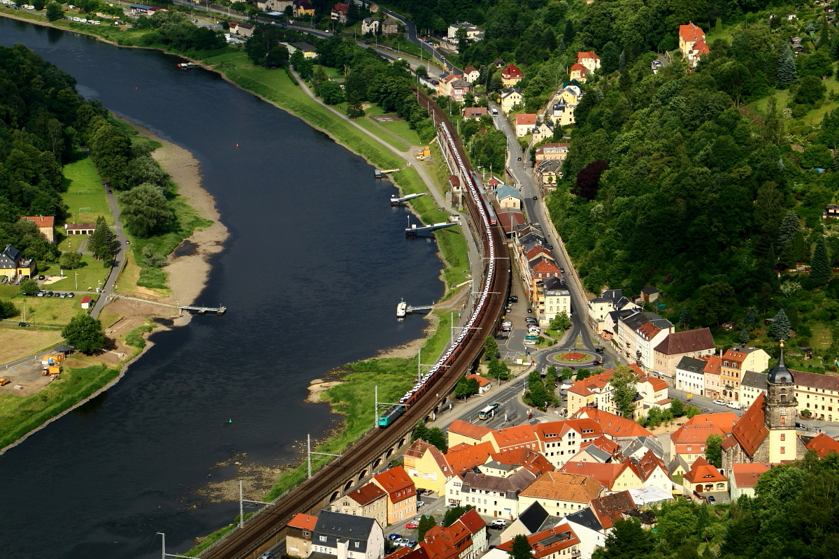 Immer wieder erstaunlich, wie viele Autos mit einer einzigen Lok bewegt werden können! ;-) Das Bild zeigt einen langen Autotransportzug mit Fahrzeugen eines bekannten tschechischen Herstellers am Nachmittag des 16.06.2017 bei der Passage der Ortslage Königstein unterhalb der namensgebenden Festung, von deren Wehrgang diese Aufnahme entstand. Im Haltepunkt des Ortes macht gerade ein S-Bahnzug nach Schöna Station.