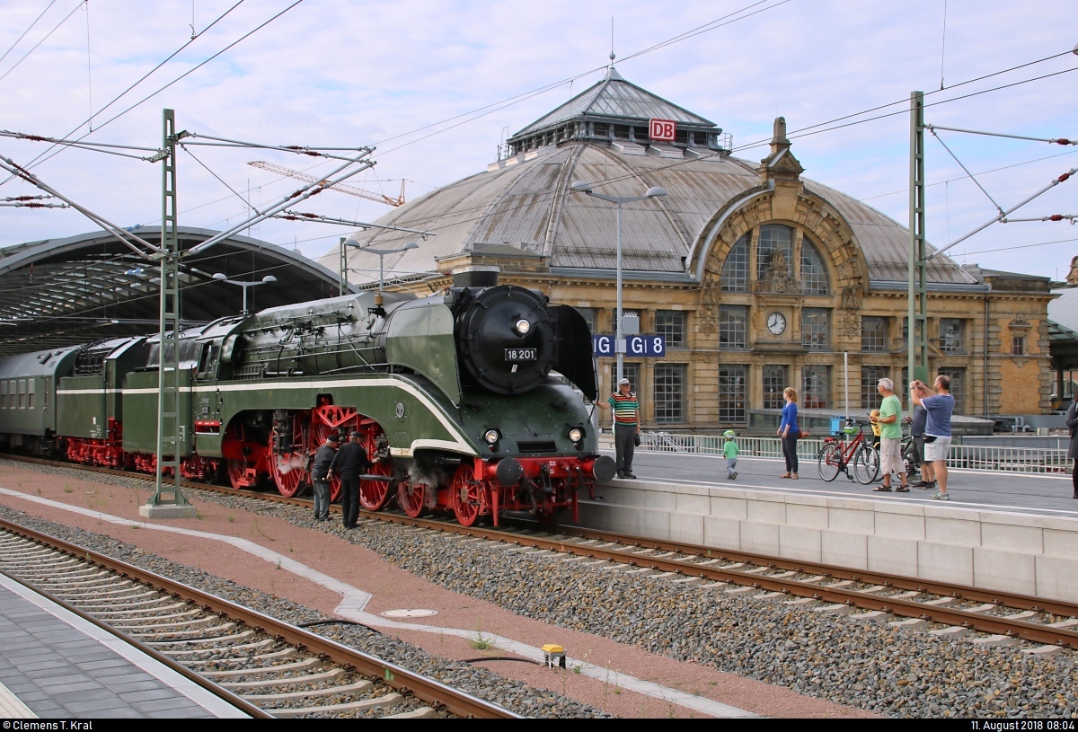 Impression mit Empfangsgebäude und 18 201 der Dampf-Plus GmbH als SDZ 56744 von Naumburg(Saale)Hbf nach Warnemünde, der in Halle(Saale)Hbf auf Gleis 9 steht. Die Hochgeschwindigkeits-Dampflok wird von zahlreichen Eisenbahnfreunden und Reisenden bestaunt und fotografiert.
Es handelte sich um die letzte Fahrt der 18 201 an die See zur Hanse Sail vor ihrem Fristablauf Ende 2018.
[11.8.2018 | 8:04 Uhr]