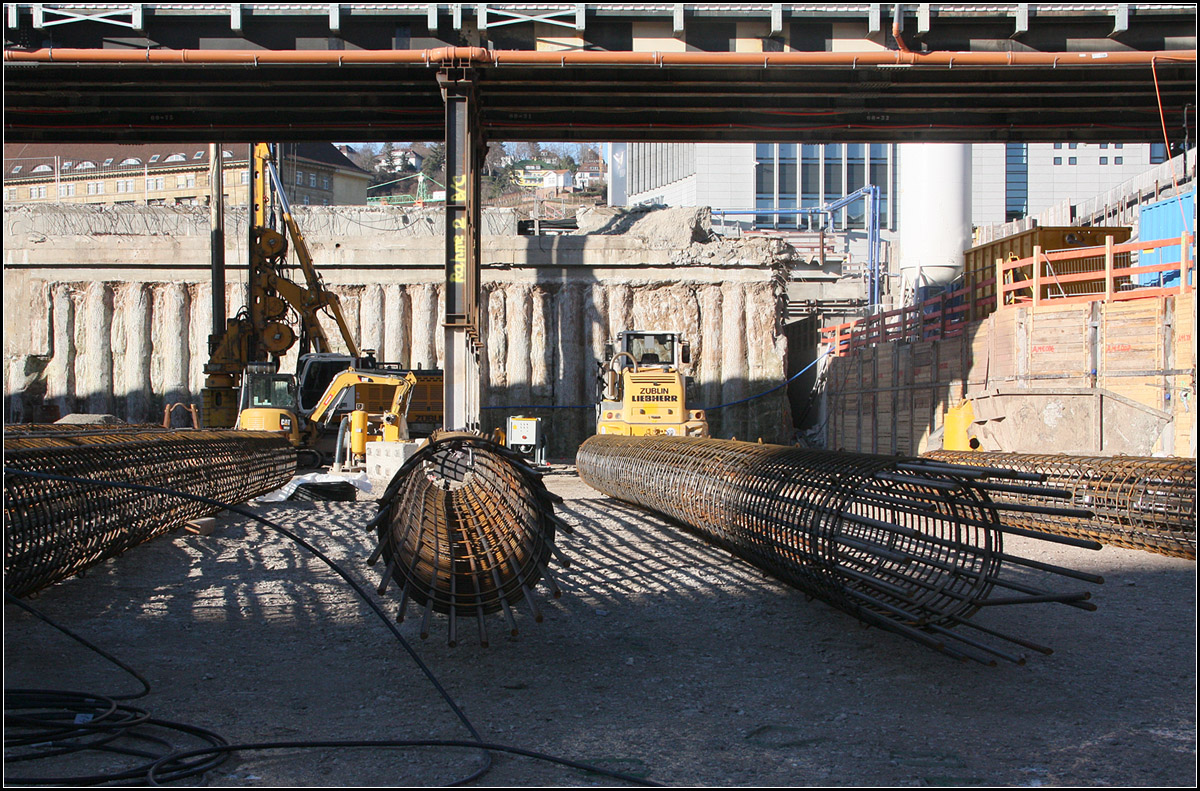 In der Bahnhofsbaugrube -

Vor ein paar Jahren noch fuhren hier in höherer Lage, noch die Züge ab. Jetzt befindet sich da die Baugrube für den neuen Stuttgarter Hauptbahnhof. Vorne unten Bewehrungsstahl wohl für Rundstützen. Oben angeschnitten eine der beiden Brücken, der das Bahnhofsgebäude mit den für die Baustelle verschobenen jetzigen Bahnsteigen verbindet. Im Hintergrund die für den unterirdischen S-Bahnhof erstellen Bohrpfahlwand, früher unter der Erde, jetzt von außen sichtbar. Die eigentliche S-Bahnstation und Tunnelstrecke liegt noch unterhalb der künftigen neuen Bahnsteige. In dem jetzt sichtbaren Bereich wird das Bauwerk abgebrochen.

Tage der offenen Baustelle, 06.01.2017 (M)