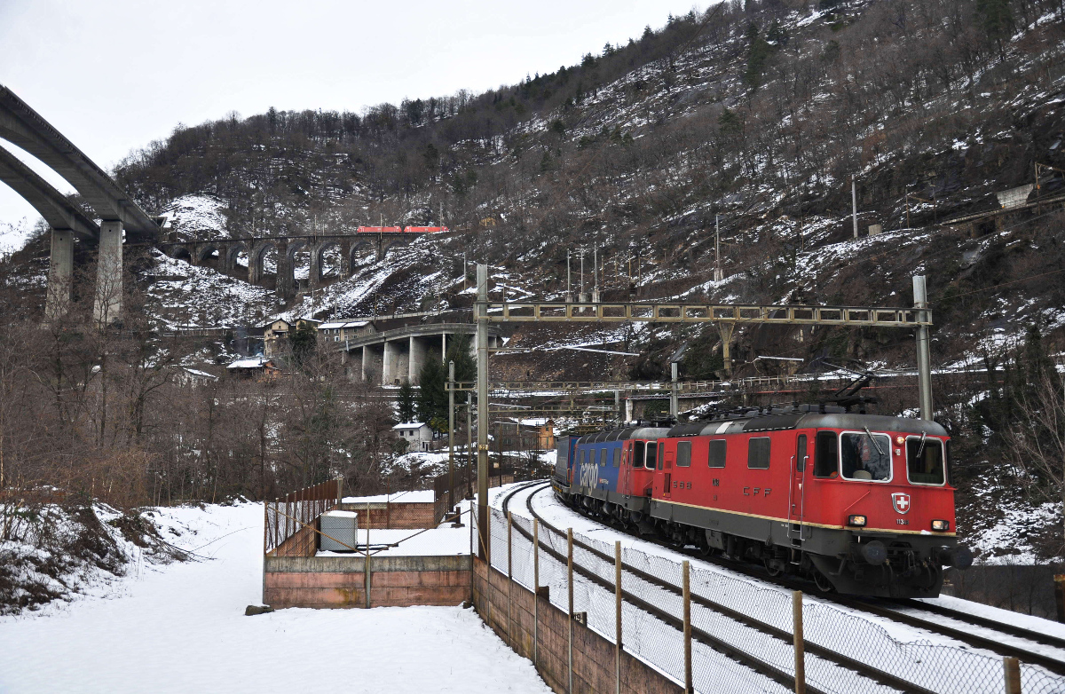 In der Biaschina sind die Re 4/4 II 11348 und die Re 620 065-3  Ziegelbrücke  mit ihrem Containerzug auf der untersten Ebene südwärst unterwegs, währenddessen zwei BR 185 der DB auf der obersten Ebene über den Pianotondo Viadukt bergwärts fahren. Aufgenommen am 23.02.2015