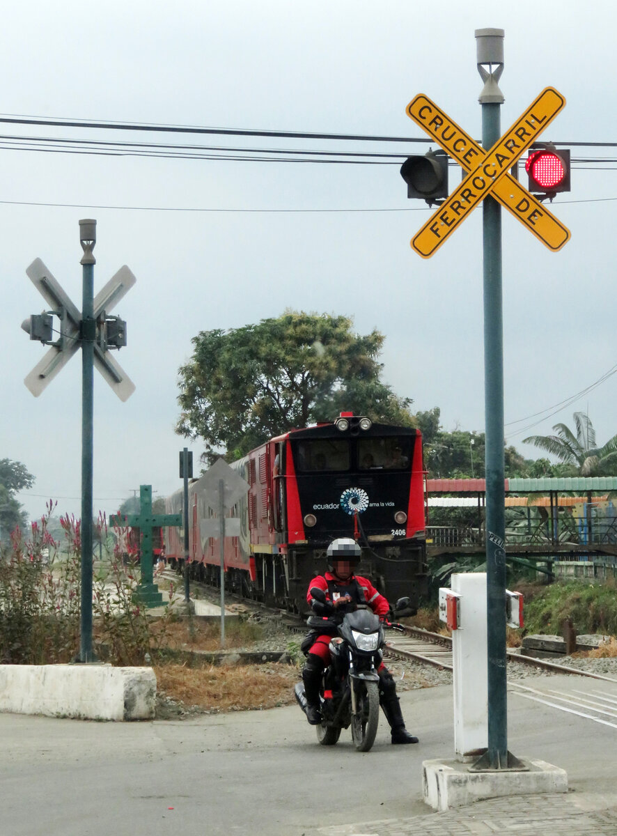 In Ecuador werden die Strassenübergange durch Motorradfahrer, die den Zug jeweils wieder auf der Strasse überholen, bewacht, obwohl das Strassensignal rot zeigt. Hier konnte der Touristenzug nach Bucay in Naranjito fotografiert werden. Naranjito, 04.08.2018